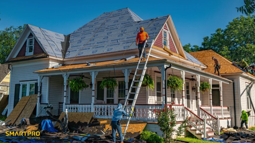 A man is repairing the roof of a house under clear blue skies.