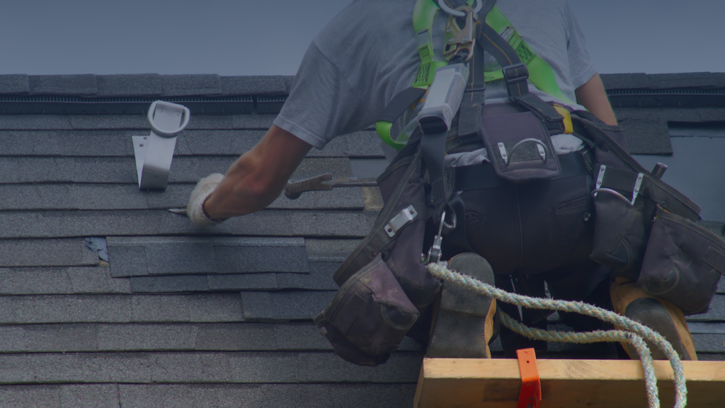 A man carefully works on a roof, using a ladder for support and safety during his task.