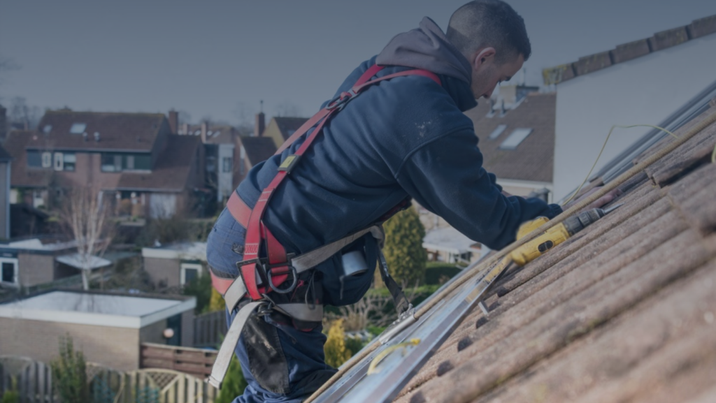 A man is working on a rooftop, engaged in maintenance or construction tasks high above the ground