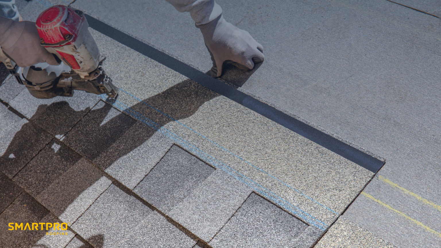 A man operates a nail gun while installing shingles on a roof during a roofing project.