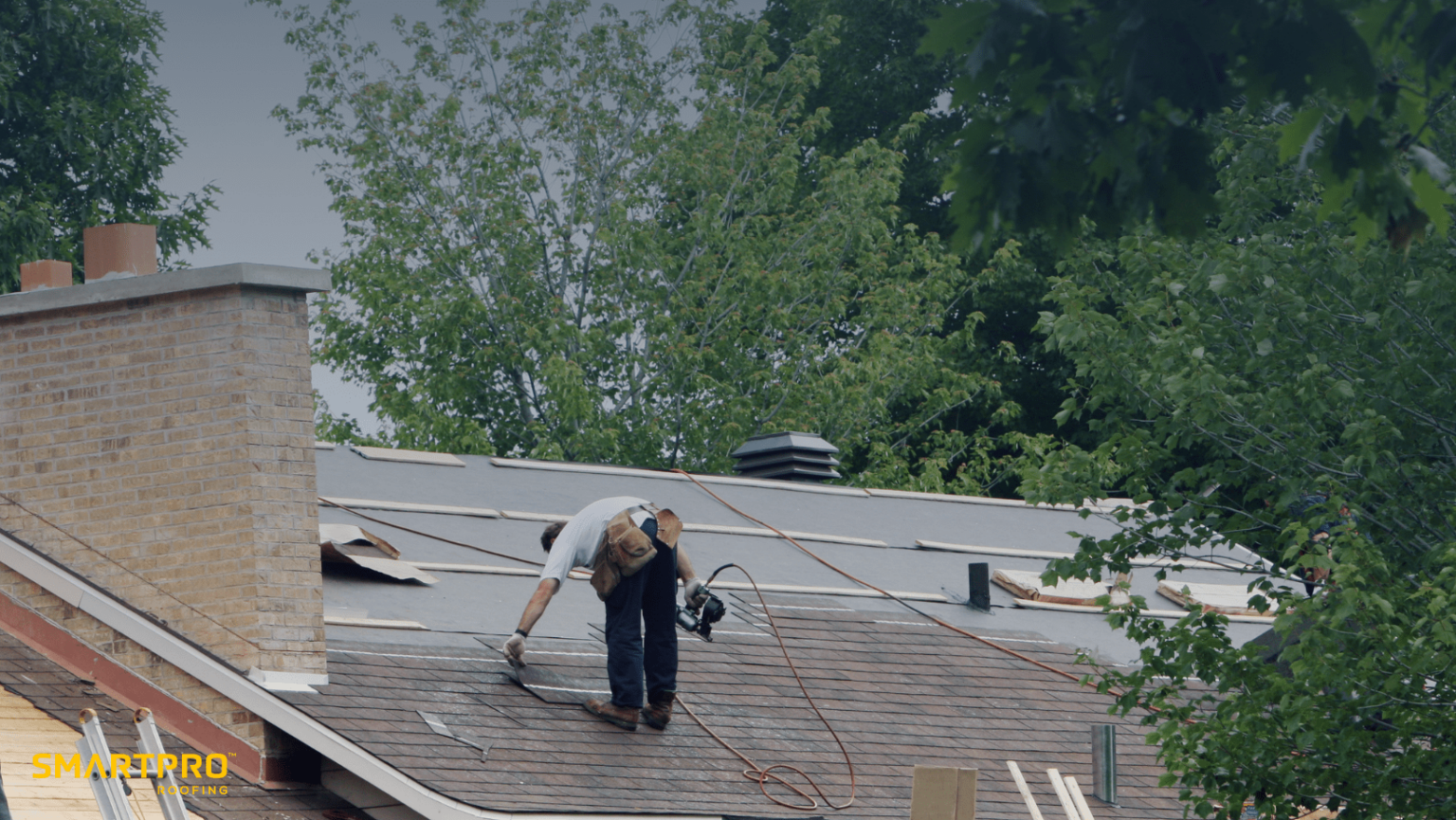 A man carefully works on a roof, using a ladder for support and safety during his task.