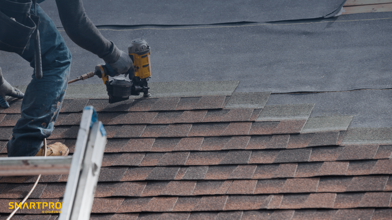 A man uses a nail gun while working on a roof, demonstrating skilled construction techniques in a residential setting.