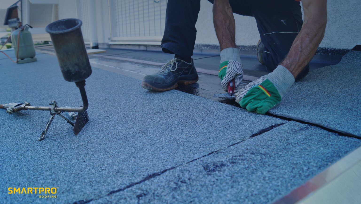 A man is using a tool while working on a roof, demonstrating construction or maintenance activities.