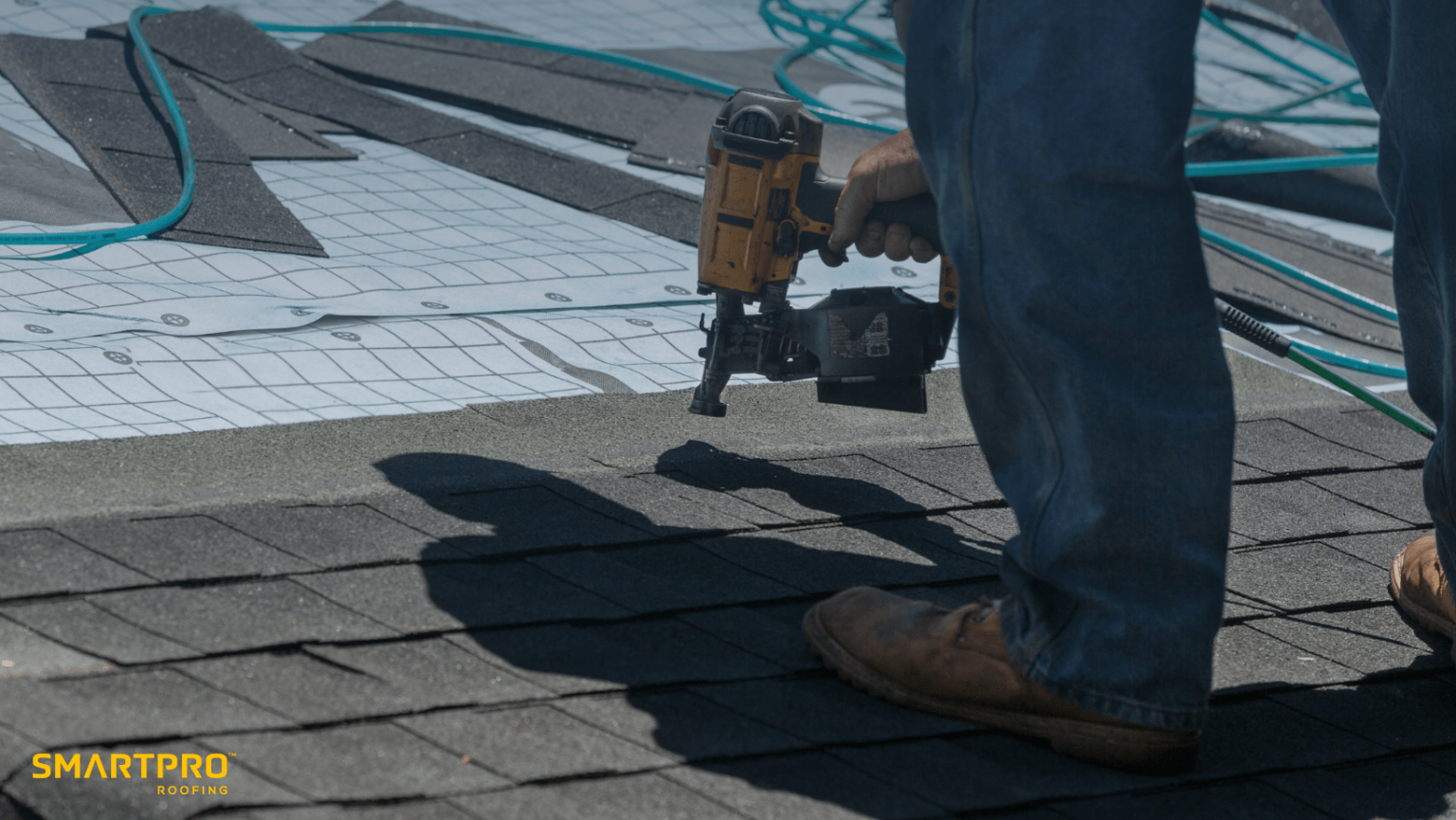 A man operates a nail gun while installing roofing materials on a house, demonstrating skilled construction work.