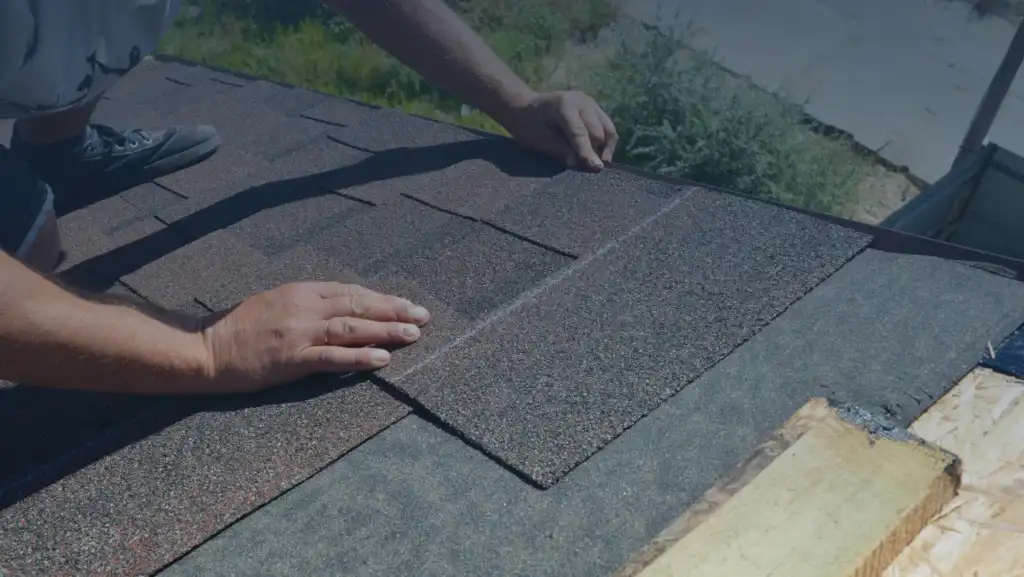 Homeowner’s Guide to Roof Replacement: Essential Tips & Tricks 12 A man carefully installs a roof shingle, demonstrating skilled craftsmanship and attention to detail in construction work.