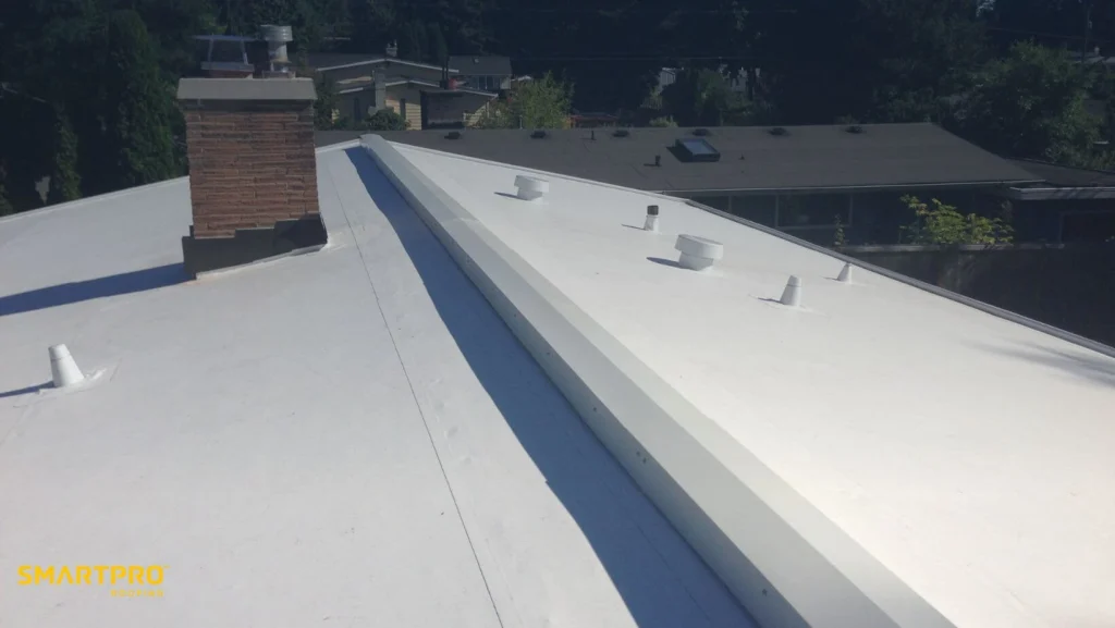 A white roof with a chimney against a clear blue sky.