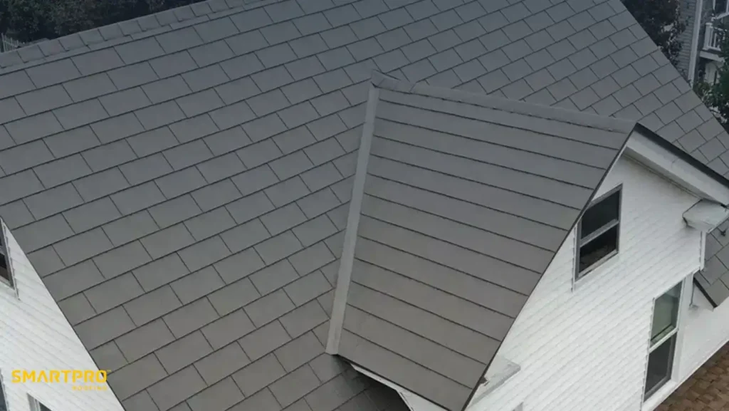 Aluminum Shingles: Benefits, Costs, Styles, and Installation Guide 12 Aerial view of a house with a freshly installed, dark gray metal roof. The roof's sleek design contrasts with the white exterior walls, conveying modernity and resilience.
