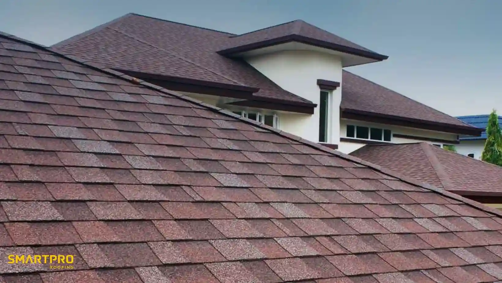 Close-up of a modern house with brown shingle roofing. The shingles form a neat pattern, conveying durability and style under a cloudy sky.