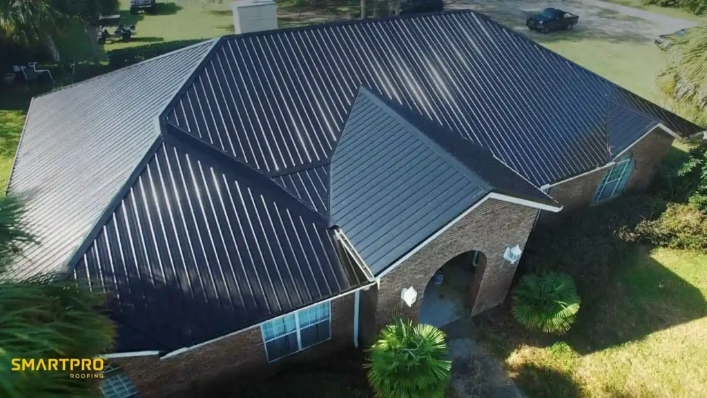 Metal Shingles vs. Standing Seam Metal Roofing 12 Aerial view of a house with a sleek, dark metal roof. The brick walls and lush greenery create a modern, inviting feel. Logo says "SmartPro Roofing."