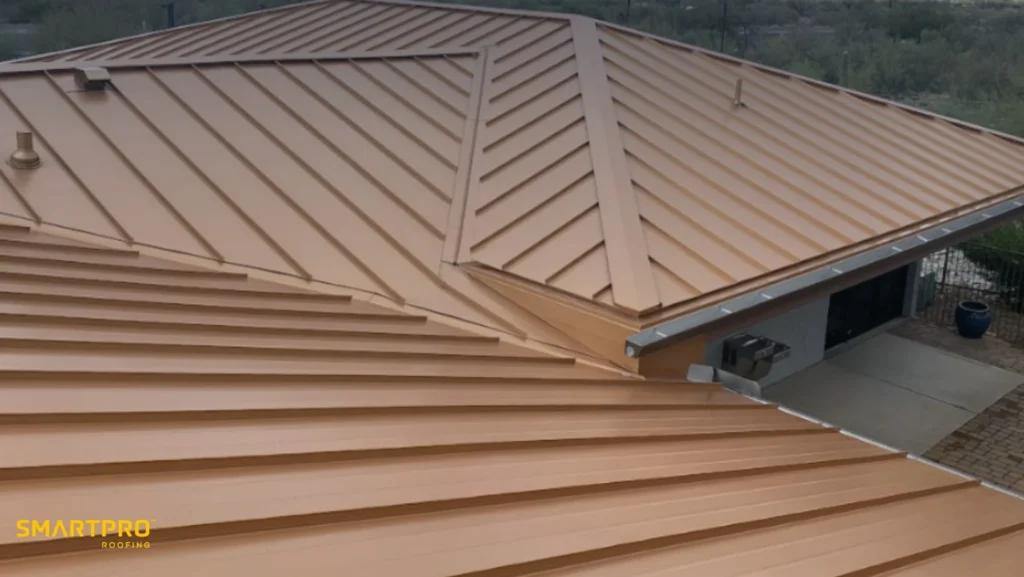 A tan metal roof with a modern design covers a residential building. The roof features clean lines and sharp angles, evoking a sleek, contemporary look.