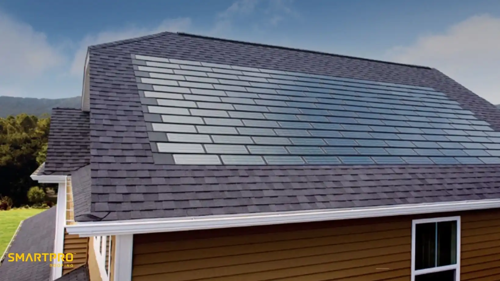 The image shows a house roof with integrated solar panels, blending seamlessly with the gray shingles. The sky is clear, creating a clean, modern feel.