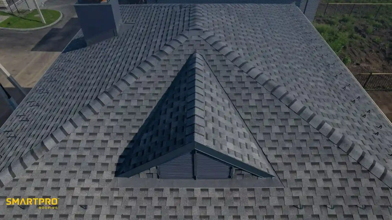 Aerial view of a roof with gray asphalt shingles in a herringbone pattern, showing clean lines and geometric symmetry, conveying durability and craftsmanship.